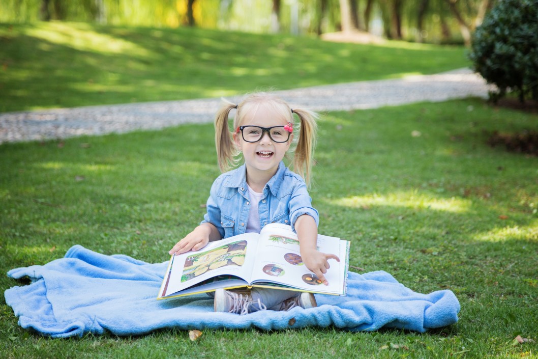 cute little girl with blonde hair in glasses reading kids book in the park education study learning t pxp j Emotional and Social Development